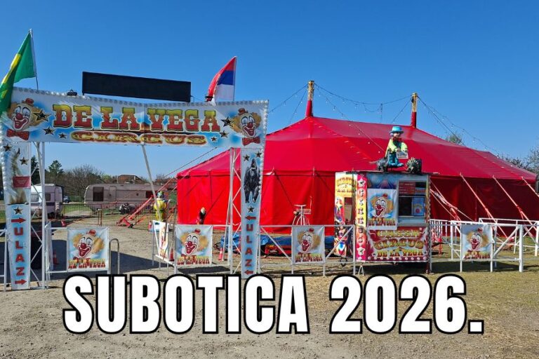 Fotografija ulaza u Cirkus Delavega na Auto pijaci u Subotici, sa velikom crvenom šatrom i dekorativnom kapijom sa klovnovima i natpisom 'SUBOTICA 2026.', spreman za premijeru.